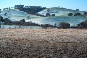 Colline verdi e campi marroni imbiancati dalla neve